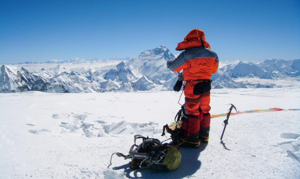 a man in winter clothes hiking a snow covered mountain